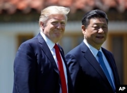 FILE - President Donald Trump and Chinese President Xi Jinping walk together after their meetings at Mar-a-Lago, April 7, 2017, in Palm Beach, Fla.