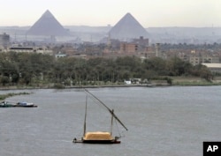 n this file photo of January 22, 2013, a traditional felucca sailing boat carries a cargo of hay as it transits the Nile river passing the Pyramids of Giza in Cairo, Egypt.