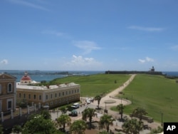 In this June 22, 2017 photo photo, tourists walk through a historic area of Puerto Rico's capital in San Juan, Puerto Rico.