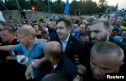 FILE - Former Georgian President Mikheil Saakashvili is surrounded by his supporters as he arrives at a checkpoint on the Ukrainian-Polish border in Shehyni, Ukraine, Sept. 10, 2017.