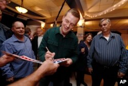 FILE - Democratic Congressional candidate Jared Golden, left, autographs a campaign sign as he and his supporters wait for election results in the 2nd Congressional District election in Lewiston, Maine, Nov. 6, 2018.
