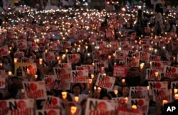 Protesters hold candles and signs during a rally denouncing Japanese Prime Minister Shinzo Abe and also demanding the South Korean government to abolish the General Security of Military Information Agreement, or GSOMIA