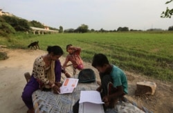 Seorang ibu memeriksa pekerjaan rumah anaknya setelah belajar di kelas yang dibuat pasangan suami-istri Veena dan Virendra Gupta, di pinggiran jalan Kota New Delhi, di India, 3 September 2020. (Foto: AP)