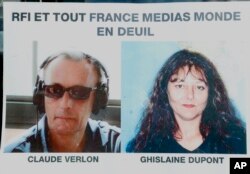 Pictures of French RFI journalists, Ghislaine Dupont and Claude Verlon on a poster headed "RFI and all France Media World in Mourning" displayed in a window in Paris, Nov. 3, 2013.
