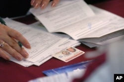 FILE - Volunteers and consulate workers help Salvadorians renew Temporary Protective Status (TPS) documentation at a church in the Van Nuys section of Los Angeles, California, Feb. 12, 2005.