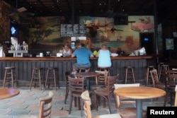 People sit at the bar of a mostly empty The Bull bar on Duval Street following Hurricane Irma in Key West, Fla., Sept. 26, 2017. A month later, tourism hasn't fully recovered.