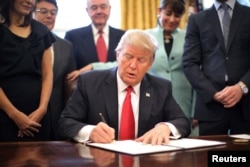 U.S. President Donald Trump signs an executive order cutting regulations, accompanied by small business leaders at the Oval Office of the White House in Washington, Jan. 30, 2017.