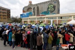 Migrants wait in queues to receive food distributed by Red Cross at the Athens port of Piraeus, March 17, 2016.