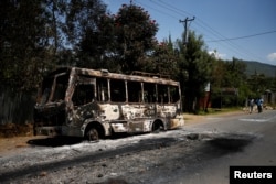 Men walk past a bus that was torched during protests in the town of Sebeta, Oromia region, Ethiopia, Oct. 8, 2016.
