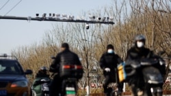 Security cameras overlook a street as vehicles pass under in Beijing, China on Nov. 25, 2021. The system will alert police and officials if people who have been grouped as a "risk" cross a border, or perform other activities. (REUTERS/Carlos Garcia Rawlins)