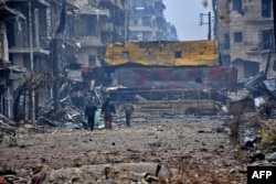Syrian pro-government forces walk in Aleppo's Bustan al-Qasr neighborhood after they captured the area in the eastern part of the war torn city, Dec. 13, 2016.