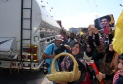 Seorang perempuan menaburkan mawar saat orang-orang berkumpul untuk menyambut kapal tanker yang membawa bahan bakar dari Suriah tiba di kota Baalbeck, di lembah Bekaa, Lebanon, 16 September 2021.