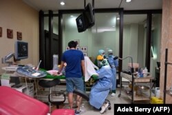 Dokter kandungan (tengah) dan perawat memakai alat pelindung saat memeriksa ibu hamil ,Jakarta, 22 April 2020, sebagai ilustrasi. (Foto: AFP/Adek Berry)