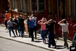 During a training exercise for London's emergency services, people walk away with their hands on their heads from the disused Aldwych underground train station in London, June 30, 2015.