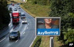 FILE - A revolving election campaign poster of Germany's anti-immigration party, Alternative fuer Deutschland, AfD, reads "Asylum fraud" as Angela Merkel, German chancellor and leader of the Christian Democratic Union party, CDU, appears partially obscured on a billboard in Duesseldorf, Germany, Sept. 14, 2017.
