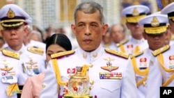 FILE - Thai King Maha Vajiralongkorn, center, holds a candle light during a ceremony at Emerald Buddha temple, in Bangkok, May 29, 2018.