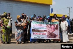 FILE - Women hold up a poster congratulating Jewel Howard Taylor, former wife of ex-President Charles Taylor, after she was re-elected senator in Monrovia, Jan. 3, 2015.
