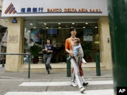 People walk near a branch of Banco Delta Asia in Macau, March 16, 2007.