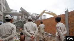 ក្រុម​សន្តិសុខ​ខណ្ឌ​ប្រាំពីរ​មករាឈរ​មើល​ការ​វាយកម្ទេច​អគារ។ ថ្ងៃ​ច័ន្ទទី​៥​ខែសីហា​ឆ្នាំ​២០១៦/ ឡេង ឡែន VOA