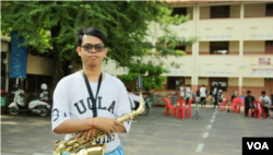 ឧត្តម ប្រាសិត កំពុងកាន់ឧបករណ៍ Saxophone។ (រិទ្ធី ឧត្តម/VOA)