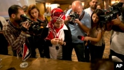 FILE - A woman draws blood from her thumb with a syringe to use to mark a ballot, in Damascus, Syria, June 3, 2014.