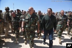 In this photo released by the Lebanese Army official website, Lebanese Prime Minister Saad Hariri, center right, walks with Lebanese Army Commander Gen. Joseph Aoun, center left, during a visit to the command center for the ongoing military operations against Islamic State militants.