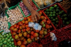 Seorang penjual sayur menerima uang dari pembeli di sebuah pasar tradisional di Jakarta, 2 Mei 2019. (Foto: Reuters)