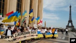 Para demonstran memegang sebagian besar bendera nasional Ukraina dan sebuah spanduk bertuliskan "Tidak untuk agresi Rusia" dalam sebuah aksi unjuk rasa di dekat Menara Eiffel di Paris, Prancis, 28 Mei 2017, menentang kunjungan Presiden Rusia Vladimir Putin ke Perancis.