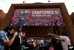 Government Attorney Carlos Gajardo, center, speaks to the press, in front of Chile's National Association of Professional Soccer, ANFP, after police investigators entered the building to look for documents and computers from the office of former president of the ANFP, Sergio Jadue, in Santiago, Dec. 3, 2015.