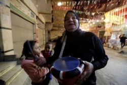 Hajja Dalal, seorang Mesaharati berusia 46 tahun, menabuh genderang untuk membangunkan umat Islam untuk sahur sebelum mereka memulai puasa Ramadhan, di Maadi di Kairo, Mesir, 13 April 2021 (Foto: REUTERS/Hayam Adel)