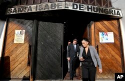 Deputy Interior Secretary Aleuy Mahmud, center, exits the Santa Isabel de Hungria Catholic Church, past a door damaged in an overnight fire-bomb attack, in Santiago, Chile, Jan. 12, 2018. On the eve of a papal visit, vandals fire-bombed three churches in the Chilean capital and warned in a leaflet that "the next bombs will be in your cassock," an unprecedented threat against the pope and a violent start to what were already expected to be the first-ever protests against Pope Francis on a foreign trip.