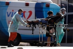 Health workers move a patient suspected of being infected with COVID-19 to the HRAN Hospital, specialized in the care of new coronavirus cases, in Brasilia, Brazil, Monday, Aug. 3, 2020. (AP Photo/Eraldo Peres)
