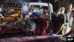 Volunteers and medical staff bring an injured man for treatment after two powerful explosions outside the airport in Kabul on Aug. 26, 2021.