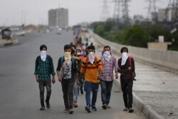 A group of Indian daily wage laborers walk along an expressway hoping to reach their homes, hundreds of kilometers away, as the city comes under lockdown in Ghaziabad, on the outskirts of New Delhi, India, March 26, 2020.