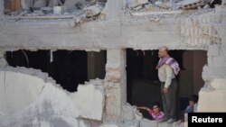 A man and boys inspect a site hit by what activists said was shelling by forces loyal to Syria's President Bashar al-Assad, Duma, Damascus, Sept. 4, 2013.