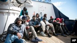 Migrants sit on the deck of the Sea-Eye rescue ship in the Mediterranean Sea, Jan. 8, 2018. Two German nonprofit groups are appealing to European Union countries to take in 49 migrants whose health is deteriorating while they are stuck on rescue ships in the Mediterranean Sea.
