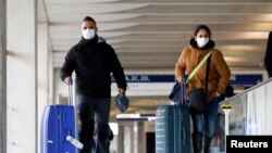 អ្នក​ដំណើរ​ពាក់ម៉ាស់​ពេល​ដែលពួកគេ​មកដល់​អាកាសយានដ្ឋាន​អន្តរជាតិ Charles de Gaulle ក្នុង​ទីក្រុង​ប៉ារីស​ប្រទេស​បារាំង។