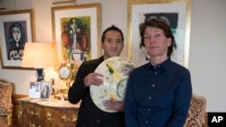 Marina Picasso, right, granddaughter of artist Pablo Picasso, and her son Florian Picasso pose with a ceramic art-work of Pablo Picasso in Cologny near in Geneva, Switzerland, Tuesday, Jan. 25, 2022. (AP Photo/Boris Heger)