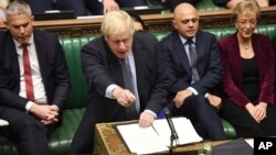 Britain's Prime Minister Boris Johnson speaks to lawmakers inside the House of Commons to update details of his new Brexit deal with EU, in London Saturday Oct. 19, 2019. At a rare weekend sitting of Parliament, Johnson implored legislators to…