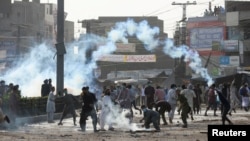 Supporters of the Tehreek-e-Labaik Pakistan (TLP) Islamist political party throwback tear gas canisters fired by police during a protest against the arrest of their leader in Lahore, Pakistan, Apr. 13, 2021. 