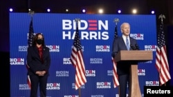 Democratic presidential candidate former Vice President Joe Biden speaks as his running mate, vice presidential candidate Senator Kamala Harris, left, looks on, in Wilmington, Delaware, Nov. 6, 2020.