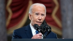 Presiden AS Joe Biden melepas masker yang ia gunakan sebelum menyampaikan pidato di Capitol Hill dalam acara peringatan satu tahun setelah serangan terhadap gedung Capitol di Washington, pada 6 Januari 2022. (Foto: Pool via Reuters/Greg Nash)