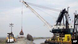 FILE - A load of rocks is dropped to patch a crater as repairs are made on the Tyler Island levee near Isleton, Calif., Feb. 15, 2017. 