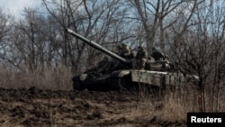 Ukrainian service members ride atop of a tank outside of the frontline town of Bakhmut, amid Russia's attack on Ukraine, in Donetsk region, Ukraine, March 4, 2023. 