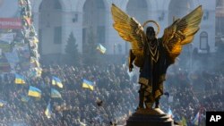 The Archangel Michael statue towers over pro-European Union activists during a rally in Independence Square in Kyiv, Ukraine, Saturday, Dec. 14, 2013.