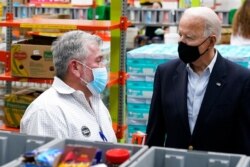 President Joe Biden speaks with a volunteer at the Houston Food Bank, Feb. 26, 2021, in Houston.