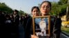 Thai mourners, carrying a portrait of late Thai King Bhumibol Adulyadej, gather in front of a replica of the royal crematorium in Bangkok, Thailand, Oct. 26, 2017.