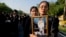 Thai mourners, carrying a portrait of late Thai King Bhumibol Adulyadej, gather in front of a replica of the royal crematorium in Bangkok, Thailand, Oct. 26, 2017.