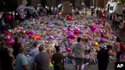 Orang-orang berdiri dekat bunga yang diletakkan untuk mengenang korban ledakan bom di Lapangan St Ann, Manchester, Inggris, Jumat, 26 Mei 2017.