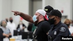 Detroit police escort a poll challenger out after he refused to leave, due to room capacity, at the TCF Center after Election Day in Detroit, Nov. 4, 2020.